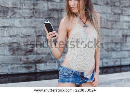 beautiful girl posing on the street and listening to music on your phone