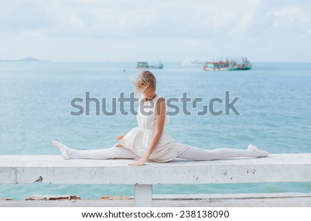 young beautiful girl posing on the pier in ballet flats and a bright dress
