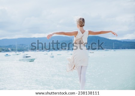 young beautiful girl posing on the pier in ballet flats and a bright dress