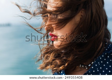 young girl posing on the street with developing hair in the wind and red lips