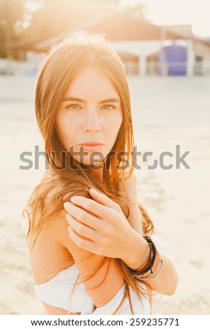 beautiful girl with long dark hair in a swimsuit and sartaj posing on the beach in the setting sun