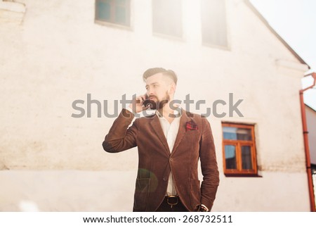young guy with a beard and a suit calling by phone