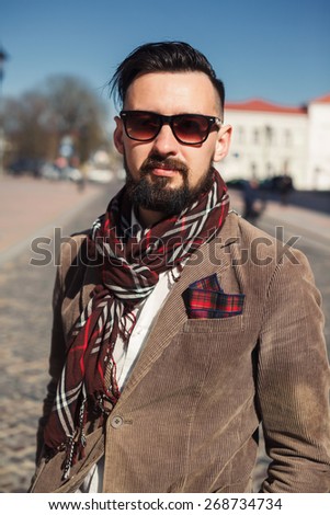 young guy with a mustache and beard with sunglasses posing on the street