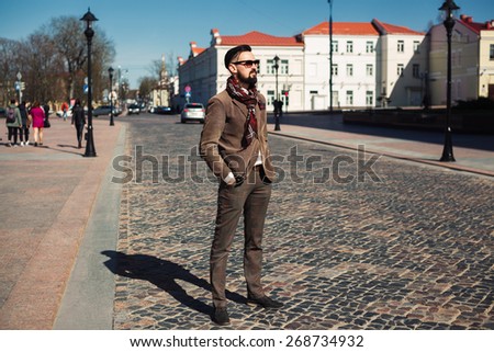young guy with a mustache and beard with sunglasses posing on the street