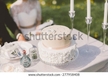 the table with the cake and wedding cake plates forks knives decor young couple sitting at the table