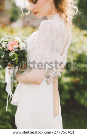beautiful bride holding a wedding bouquet of flowers and posing on the lawn
