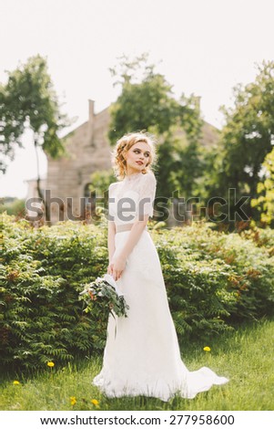 beautiful bride holding a wedding bouquet of flowers and posing on the lawn