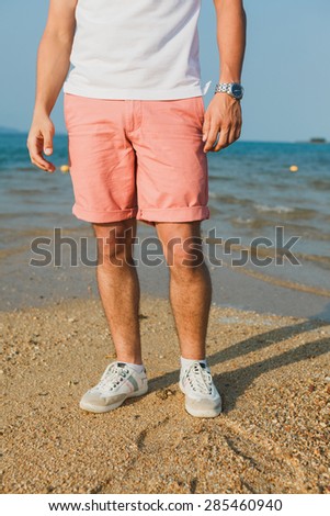 young guy in a white t-shirt and red shorts feet in sneakers
