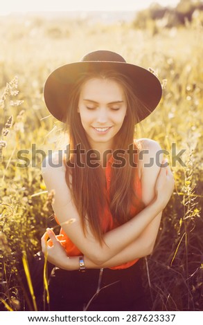 beautiful young girl in a black hat posing in the sun and smiles
