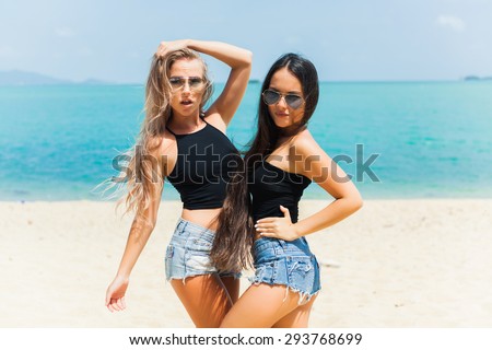 beautiful girls in shorts and bikinis and sunglasses fun walk on the beach and smiling best friend having fun