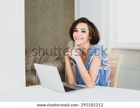 beautiful brunette girl working at home on the computer a laptop writes emails and smiles