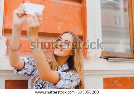 Happy travel young girl selfie taking pictures of herself isolated over white background, Fashionable attractive woman taking a self portrait. Selfie, indoor, horizontal, over white wall