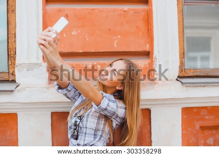 Beautiful urban woman taking picture of herself, selfie. Filtered image.self portrait of herself while networking. Travel and technology outdoors.