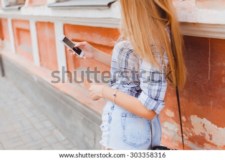 young girl talking on the phone in the street surfing on the phone smiling