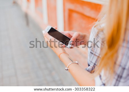young girl talking on the phone in the street surfing on the phone smiling, apple style, iphone call