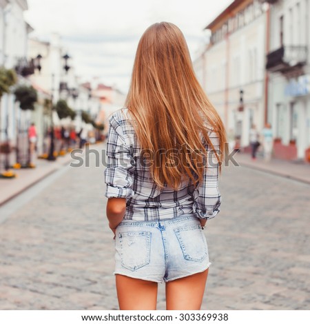 Outdoor summer city evening hipster portrait of young blonde happy smiling woman having fun outdoor in the city in Europe in evening with camera travel,look away from camera,ready for travel