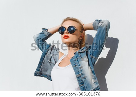 Outdoor fashion portrait of young happy pretty smiling woman,posing on white,wear stylish street style outfit trendy sunglasses,positive mood.Urban city style,summer accessories.denim style