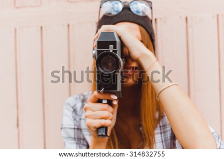 lifestyle sunny lifestyle fashion portrait of young stylish hipster woman walking on street,with video camera,smiling enjoy weekends,make a video of her travel,old retro videocamera,vintage