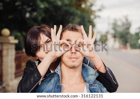 Funny laughing couple, sensual fashion portrait of young couple in love, having fun, relaxed end end enjoy time together at the street, beautiful sunset, elegant trendy clothes, romantic atmosphere.