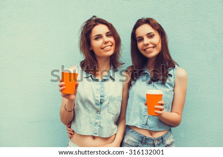 two girls girlfriends sisters twins drink coffee on the street