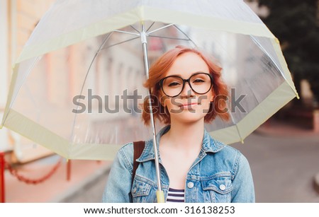cute teen girl walking alone with umbrella,and smiling. Street style fashion details, bright blue romper,backpack and trendy jewelry, posing on the street, bright colors.