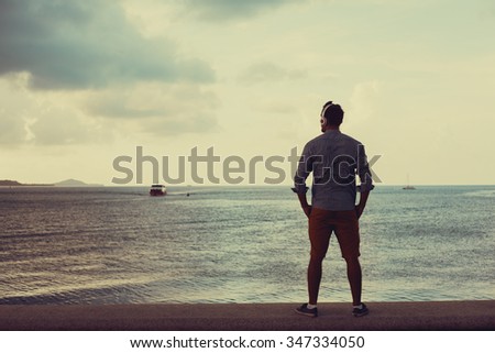 Silhouette of  a  man posing  outdoor not  he  beach of  sand,tropical island,looking  away from the camera,coolest style,full leigh portrait ,ocean view,California beach,LA,east coast