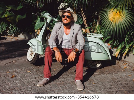 handsome in a light jacket, hat and red trousers, sunglasses with mustache and beard about posing retro scooter, fashionable clothes, brutal man, stylish outfit, Tiffany, walk down the street