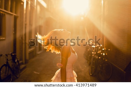 young girl posing in the street on sunset lights, hair style, amazing, drees, amsterdam city, moods happy dance
