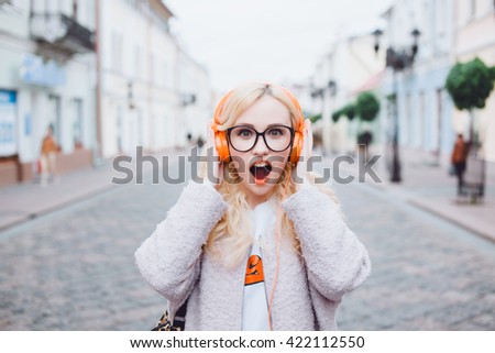 young girl listening music in headphones, urban street style,outdoor street style hipster dj woman in yellow sunglasses and dj headphones listen music and smile, orange, crazy style, street shoot,