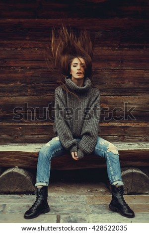 young beautiful brunette girl in a warm knitted sweater in jeans and boots posing on the street, on the street porttrait, to close the model
