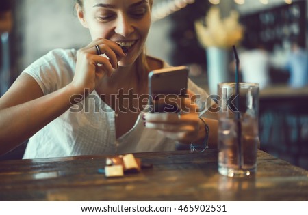 young pretty brunette woman eat chocolate in cafe, using smartphone, touch screen display, sweet food, tasty breakfast, close up portrait, hipster girl, fanny
