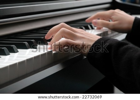 A closeup of a pair of hands as they press on piano keys.