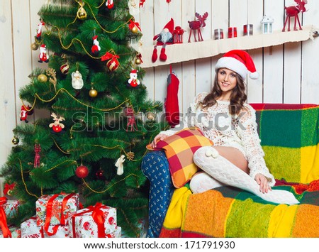 a beautiful young girl in a cap of Santa Claus in the new year interior