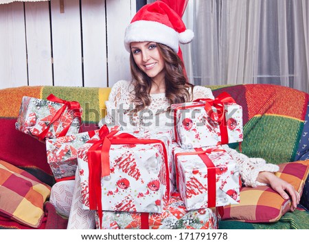 a beautiful young girl in a cap Santa Claus near gifts in the new year interior