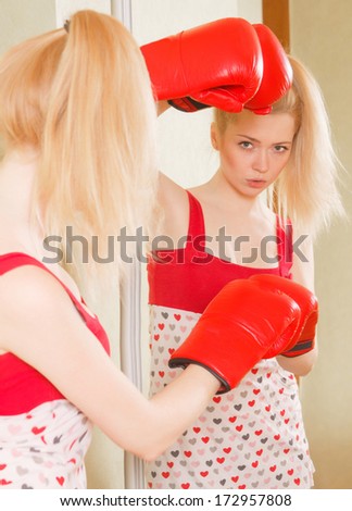 pretty blonde girl in Boxing gloves looks in the mirror