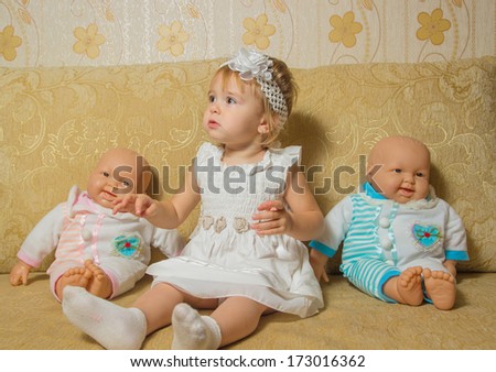 little girl with the dolls sitting on the couch
