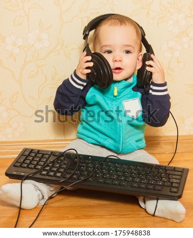 the little boy played with headphones and a keyboard sitting on the floor