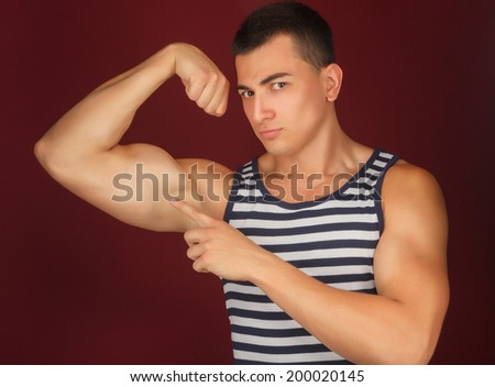 athletic guy in the striped shirt shows its muscle on the background
