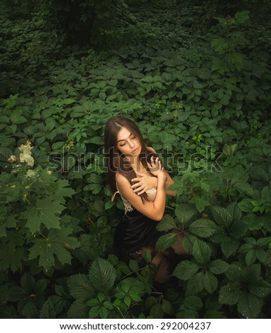 beautiful girl in dress posing in the green forest