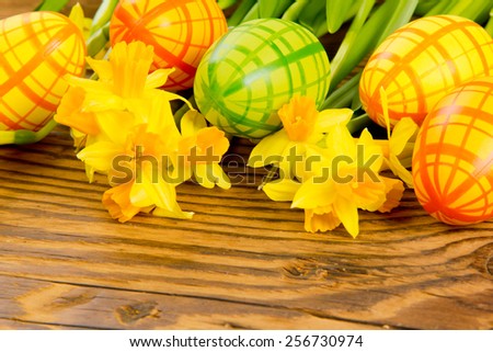 Easter eggs with daffodil blooms on wooden board