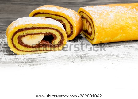 Photo of sliced roll cake on wooden board with white space for text