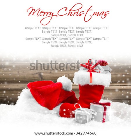 Photo of Santa cap, shoe and gifts with falling snow and white space