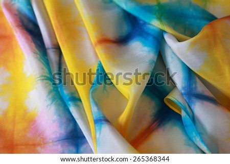 Silk background in vibrant colors.Rippled surface of light silk dyed in shades of nature in summer : yellow, green, red, blue, turquoise, creating irregular pattern. Expression of joy, happiness.
