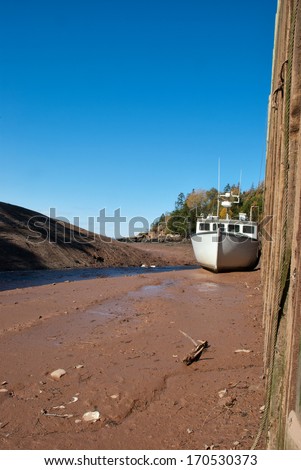 Fishing boat high and dry at low tide in Sand River, Nova Scotia.