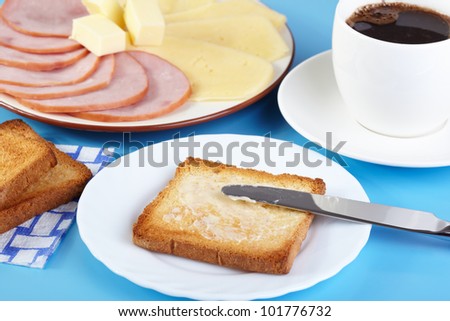 Breakfast. A cup of coffee and toasts with butter, cheese and ham