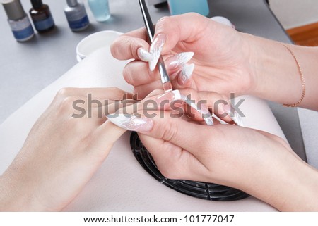 Manicure. Master make nail extension: drawing of white gel on free edge of a nail