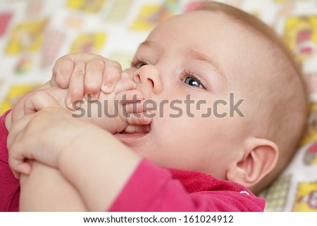 The baby pulls a foot in a mouth