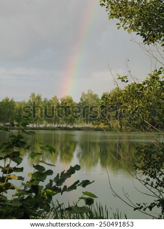 Bohemian pond after the storm with rainbow on a dark cloudy sky, typical nature in South Bohemia
