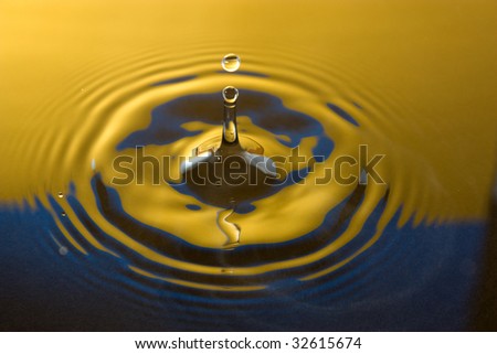 Tall water drop gold and blue with colors reflected in water and ripples