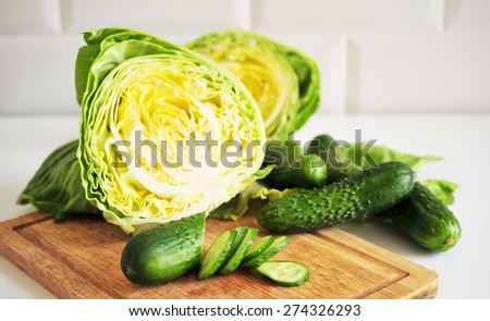 Sliced fresh cucumbers and cabbage, olive olive\'s jug on the kitchen desk